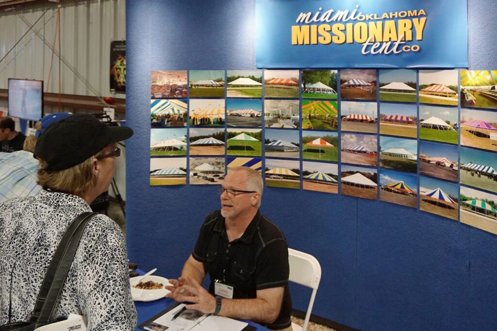 Miami Missionary Tent Co general manager talking with customers at tradeshow booth about our pole tents