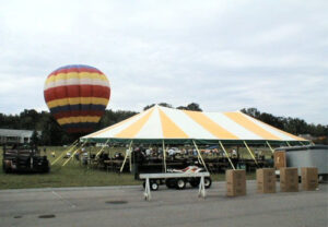 Yellow and white tent set up with a hot air balloon behind it
