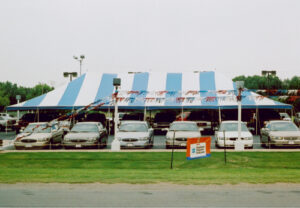 Blue and white pole tent set up at a car lot