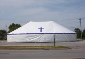 All white revival tent with purple cross set up for a revival