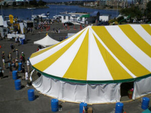 White and yellow event tent set up by a lake