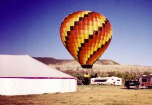 Pole tent set up with a hot air ballon behind it