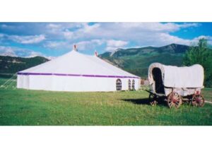 White pole tent with purple valance and windows set up overseas