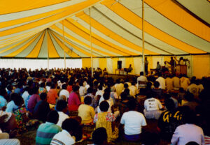 Large yellow and white pole tent set up for a revival
