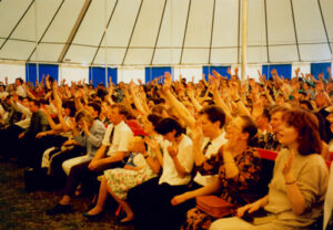People worshipping under a large all white revival tent