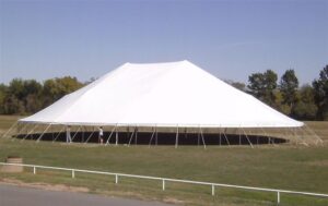 Large all white pole tent set up in a field