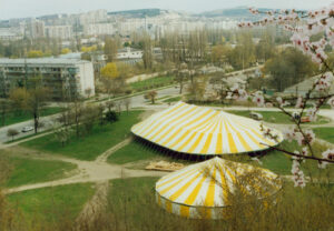 Two yellow and white pole tents set up in a field