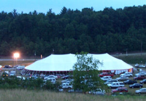 Large all white event tent with cars parked all around it