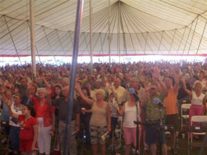People worshipping under an all white pole tent
