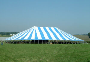 A large blue and white event tent set up in a field