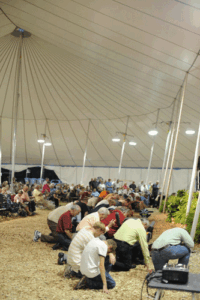 People kneeling and praying under a large revival tent