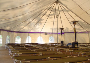 Large white event tent set up with cots for disaster relief